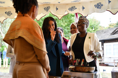 Meghan, Duchess of Sussex jokes with her mother Doria Ragland as she helps to prepare food at the launch of a cookbook with recipes from a group of women affected by the Grenfell Tower fire at Kensington Palace in London, Britain September 20, 2018. Ben Stansall/Pool via Reuters