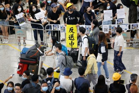 Anti-extradition bill protesters hold up a sign for arriving travellers during a protest at the arrival hall of Hong Kong airport
