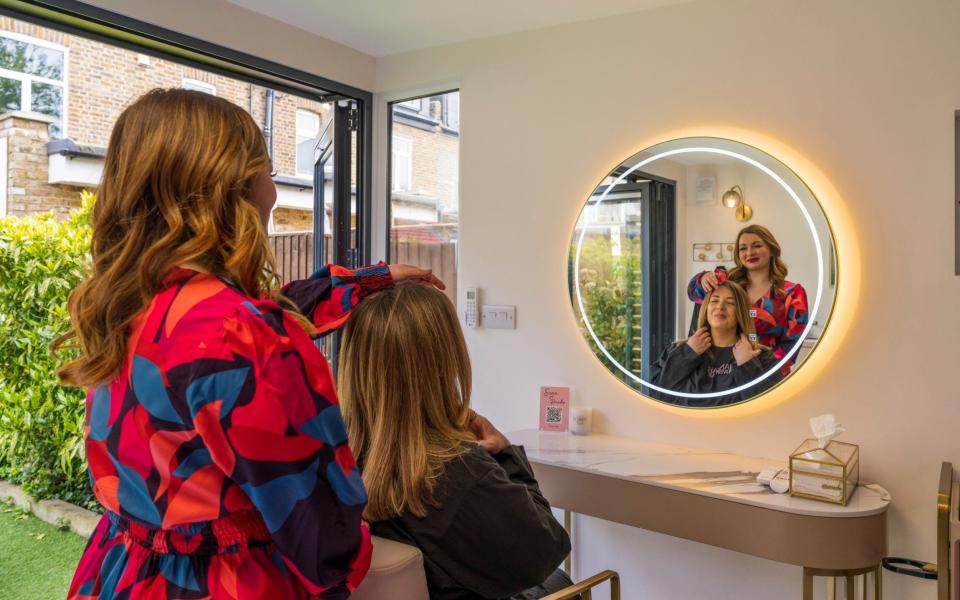 Hannah in her garden room-cum-hair salon; with a customer, above