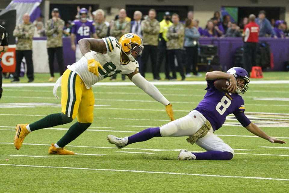 Minnesota Vikings quarterback Kirk Cousins (8) slides to the turf ahead of Green Bay Packers outside linebacker Preston Smith (91) during the first half of an NFL football game, Sunday, Nov. 21, 2021, in Minneapolis. (AP Photo/Jim Mone)