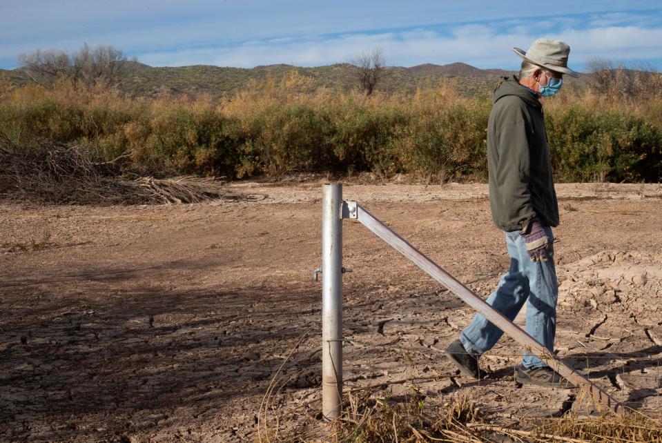Peter Else walks next to a gate post that was buried by over 3 feet of clay sediment in 2017 flooding on his property by the San Pedro River north of Mammoth, Arizona.