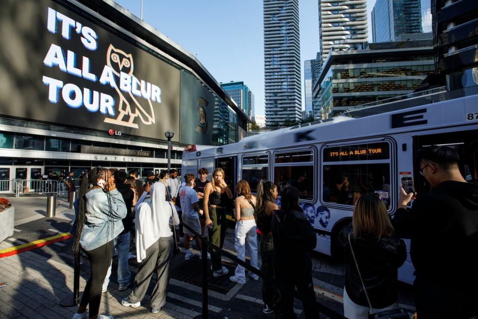 Fans of Drake are photographed in front of a bus serving as a merchandise stand near Scotiabank Arena ahead of his concert in Toronto on October 6, 2023.