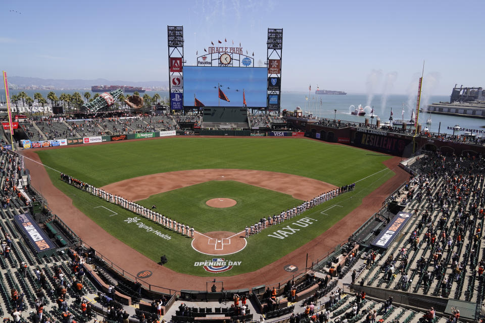 The San Francisco Giants, left, and the Colorado Rockies stand along the baselines during an opening day flyover before their baseball game Friday, April 9, 2021, in San Francisco. (AP Photo/Eric Risberg)