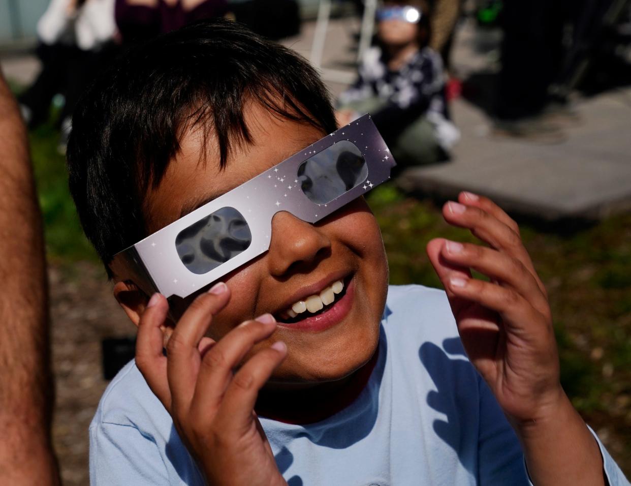 Kai Hysell, 7, of Bloomfield Hills, watches the solar eclipse with his family at the Cranbrook Institute of Science in Bloomfield Hills on Monday, April 8, 2024.