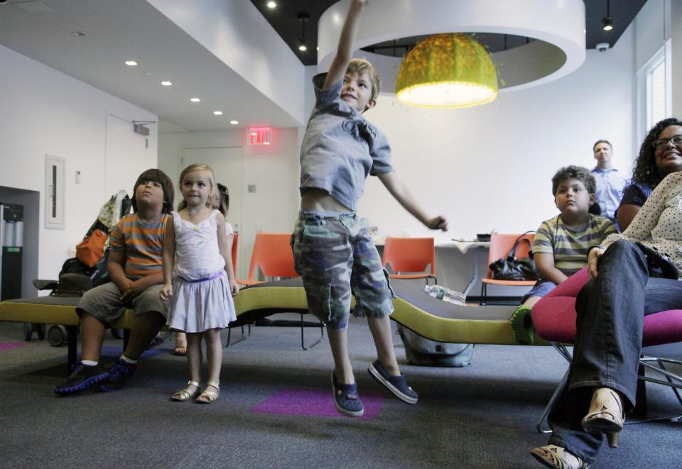 In this Sept. 5, 2012, photo, Aidan Lain, 7, jumps while watching "Kinect Sesame Street TV" at the Sesame Street Workshop in New York. "Kinect Sesame Street TV", launching Tuesday, Sept. 18, 2012, uses Kinect, a motion and voice-sensing controller created by Microsoft, to give Elmo, Big Bird and the rest of the Sesame Street crew a chance to have a real two-way conversation with their pint-sized audience. The effort represents the next step in the evolution of television, adding an interactive element to what's still largely a passive, lean-back experience. (AP Photo/Mark Lennihan)