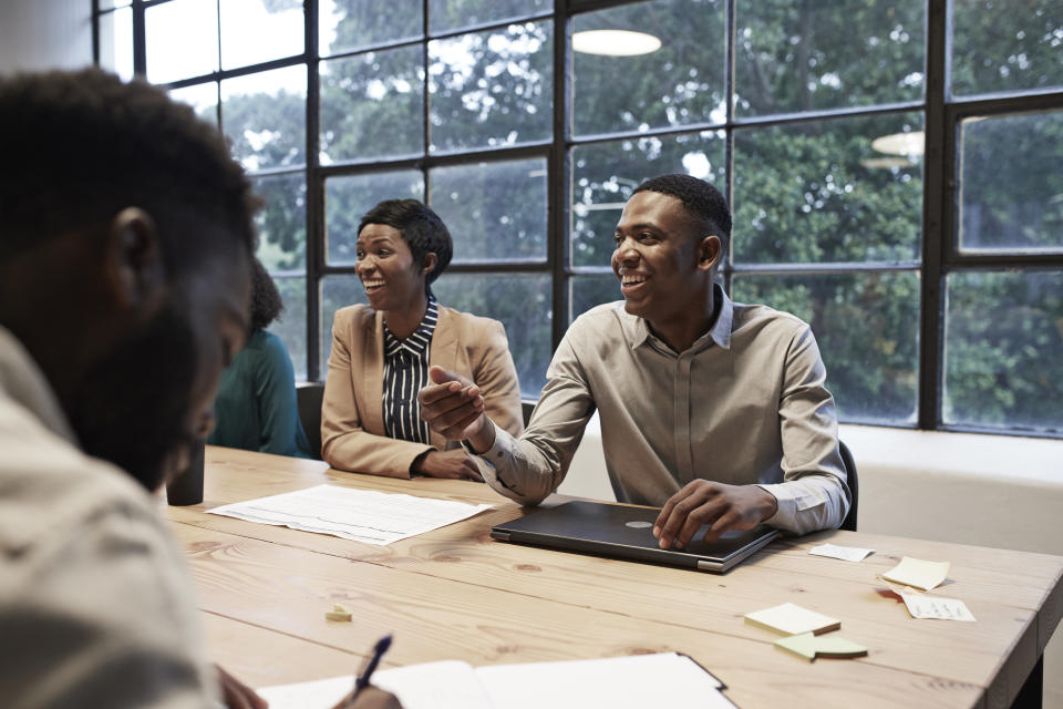 Smiling business colleagues sitting in conference room during office meeting at workplace