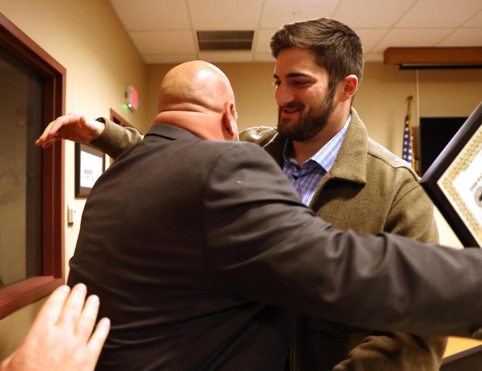 Raynham Police Det. Louis F. Pacheco, left, is congratulated by Bryce Shaw at Town Hall on Tuesday, Jan. 23, 2024. Selectmen presented the Raynham Recognition Award to Pacheco, who is the Raynham school resource officer and B-R head football coach.