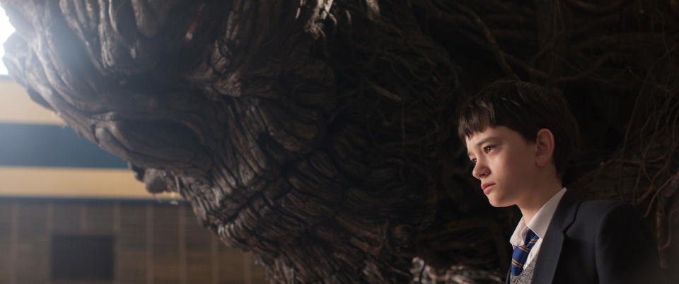This image released by Focus Features, Lewis MacDougall appears with The Monster, voiced and performed by Liam Neeson, in a scene from "A Monster Calls." (Focus Features via AP)