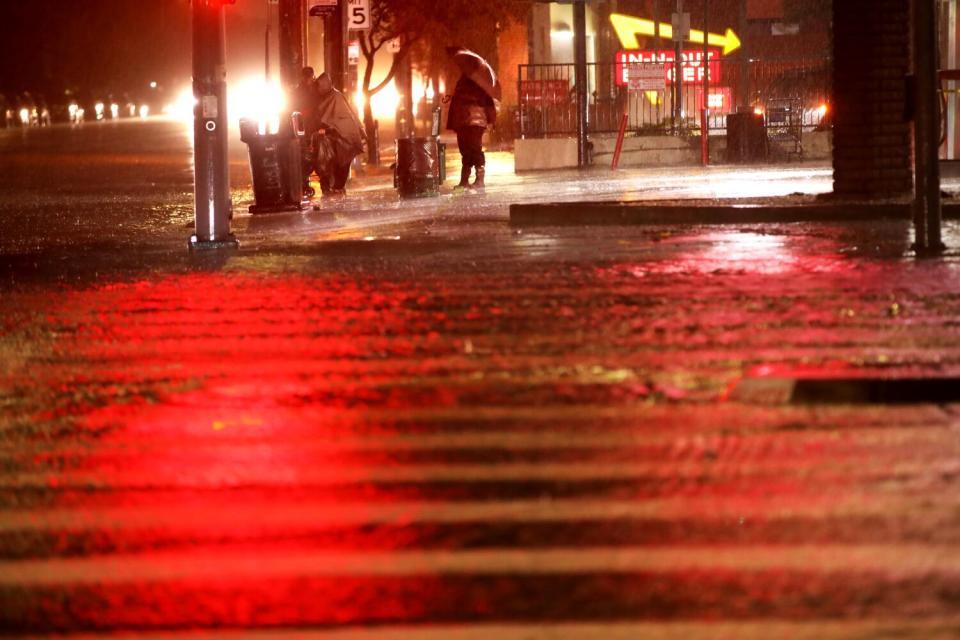 A man waits for a bus during a downpour in Encino.