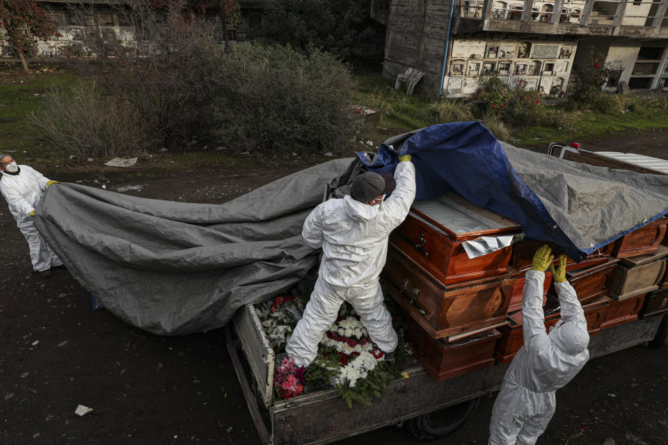 Workers collect and stack the coffins of people that have been recently cremated amid the new coronavirus pandemic, at the La Recoleta cemetery in Santiago, Chile, Sunday, June 28, 2020. The coffins are collected, destroyed, and processed by a company specialized in organic waste. (AP Photo/Esteban Felix)