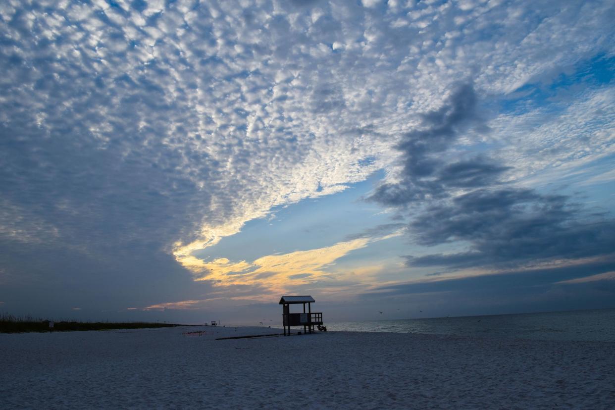 Sunrise over a lone lifeguard stand, Navarre Beach, Florida, dramatic clouds