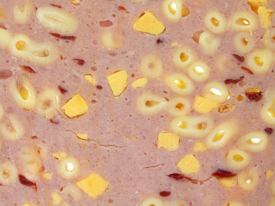 Deli meat with pieces of macaroni pasta and chunks of cheese in it