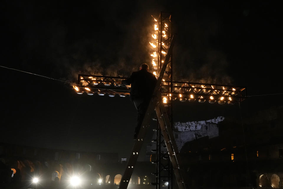 A worker lights candles on a cross at the Colosseum prior to the start of a Via Crucis (Way of the Cross) torchlight procession on Good Friday, in Rome, Friday, March 29, 2024. (AP Photo/Gregorio Borgia)