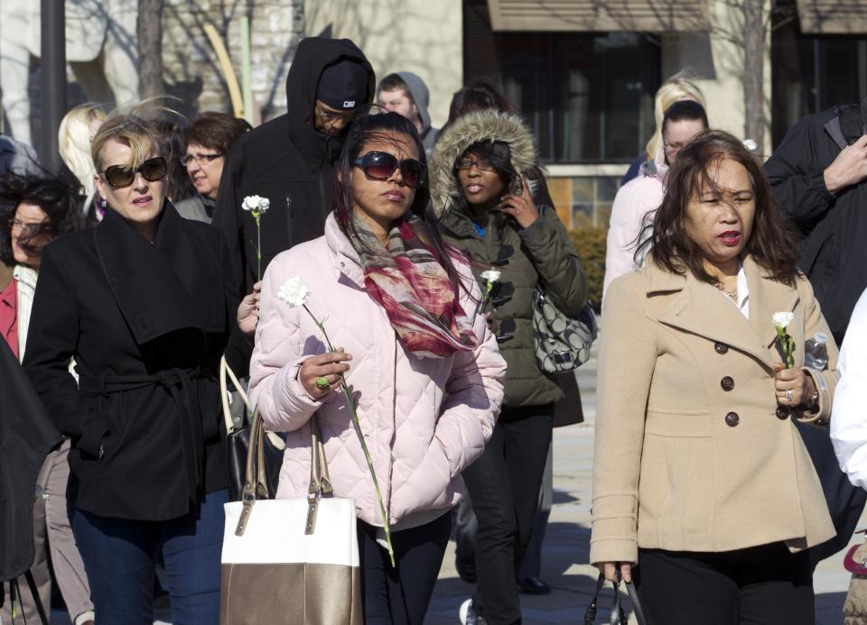 Columbia Mall employees holding carnations walk to the mall which is expected to be open at 1;00 p.m. , on Monday Jan. 27, 2014 in Howard County, Md. Three people died Saturday in a shooting at a mall in suburban Baltimore, including the gunman. ( AP Photo/Jose Luis Magana)