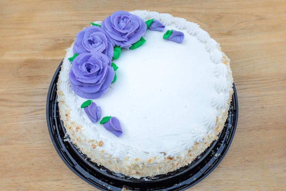 Costco round sheet cake topped with purple frosting roses