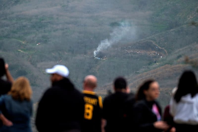 Un grupo de personas ve el humo procedente del helicóptero siniestrado en el que falleció el exjugador de baloncesto Kobe Bryant y otras cuatro personas en Calabasas, California, EEUU.