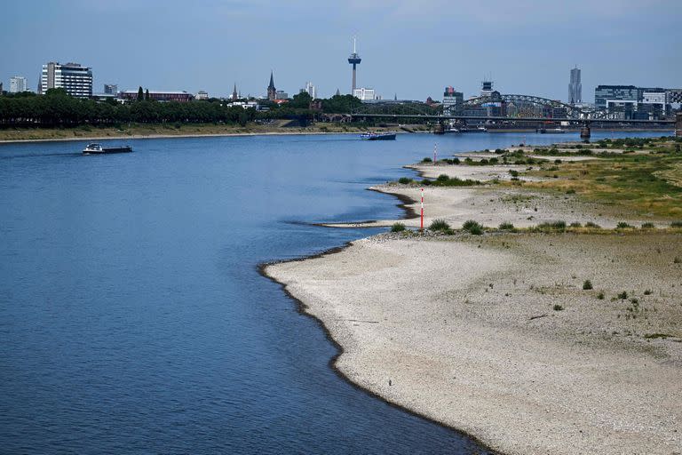 Los barcos navegan más allá del lecho del río Rin, parcialmente seco en Colonia, Alemania occidental, el 18 de julio de 2022