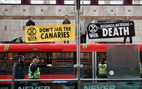 Climate change activists held up banners on the roof of a DLR train at Canary Wharf station - Credit: AFP