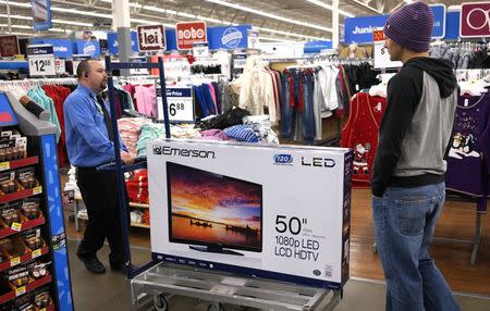 A Walmart employee helps a customer with a 50" TV on sale for $218 on Black Friday in Broomfield, Colorado November 28, 2014. REUTERS/Rick Wilking