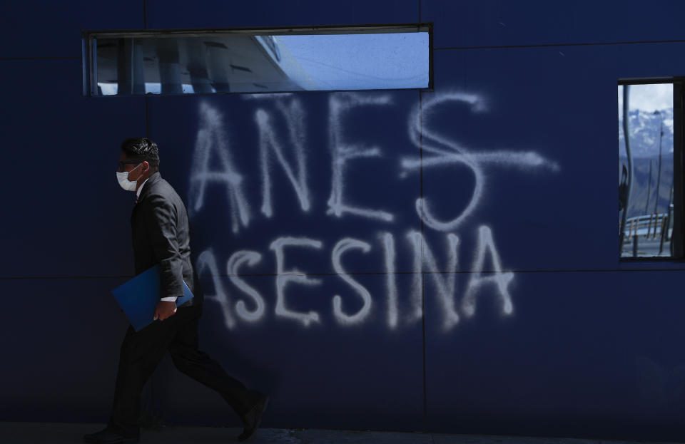 Un hombre con mascarilla para protegerse del COVID-19 camina junto a un grafiti que dice "Anes asesina" en referencia a la presidenta interina de Bolivia, Jeanine Áñnez, durante una protesta contra el aplazamiento de las elecciones presidenciales, en El Alto, Bolivia, el jueves 13 de agosto de 2020. (AP Foto/Juan Karita)