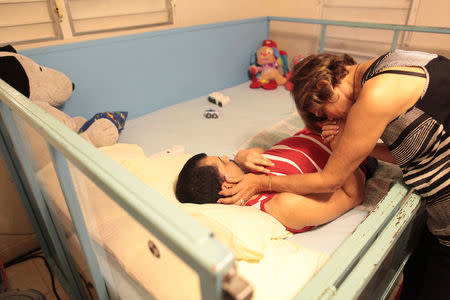 Ramona Febo-Boarman touches her son Joey while he lies in his bed at their home in Bayamon, Puerto Rico, December 1, 2016. REUTERS/Alvin Baez