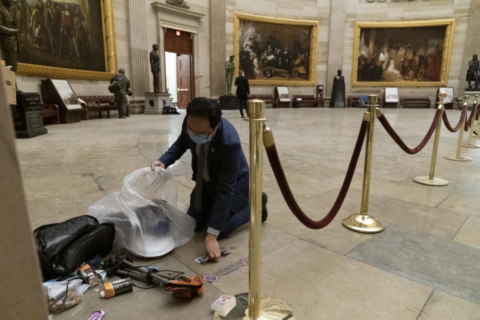 Rep. Andy Kim, D-N.J., cleans up debris and personal belongings strewn across the floor of the Rotunda in the early morning hours of Thursday, Jan. 7, 2021, after protesters stormed the Capitol in Washington, on Wednesday. (AP Photo/Andrew Harnik)