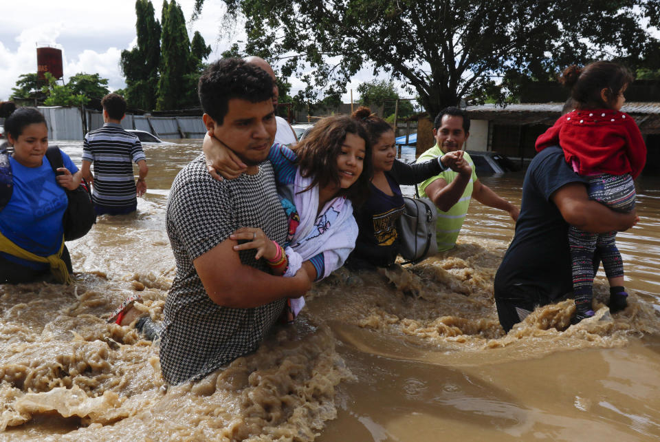 People help each other wade through a flooded street in the aftermath of Hurricane Eta in Jerusalen, Honduras, Thursday, Nov. 5, 2020. The storm that hit Nicaragua as a Category 4 hurricane on Tuesday had become more of a vast tropical rainstorm, but it was advancing so slowly and dumping so much rain that much of Central America remained on high alert. (AP Photo/Delmer Martinez)