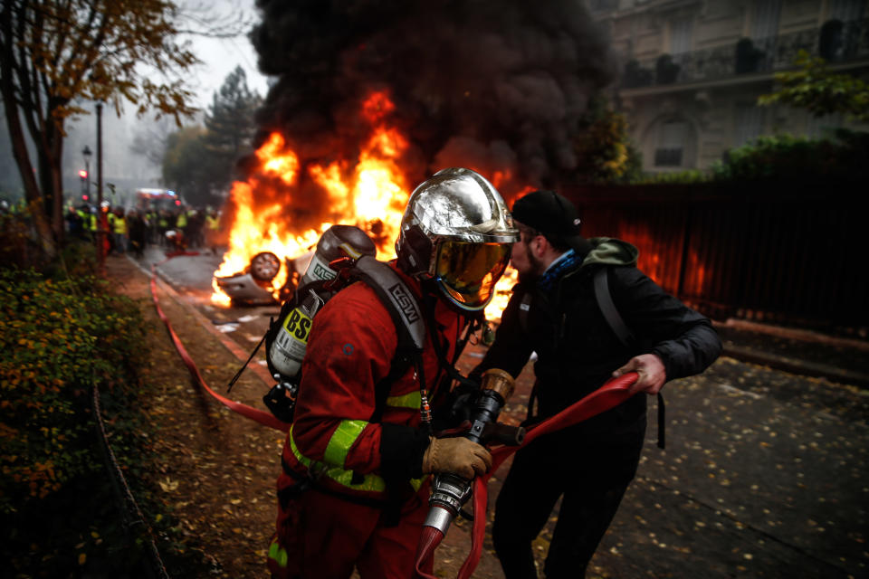 Firefighters work to extinguish a burning car on the sideline of a demonstration, against rising oil prices and living costs, on Dec. 1, 2018, in Paris. (Photo: Abdulmonam Eassa/AFP/Getty Images)