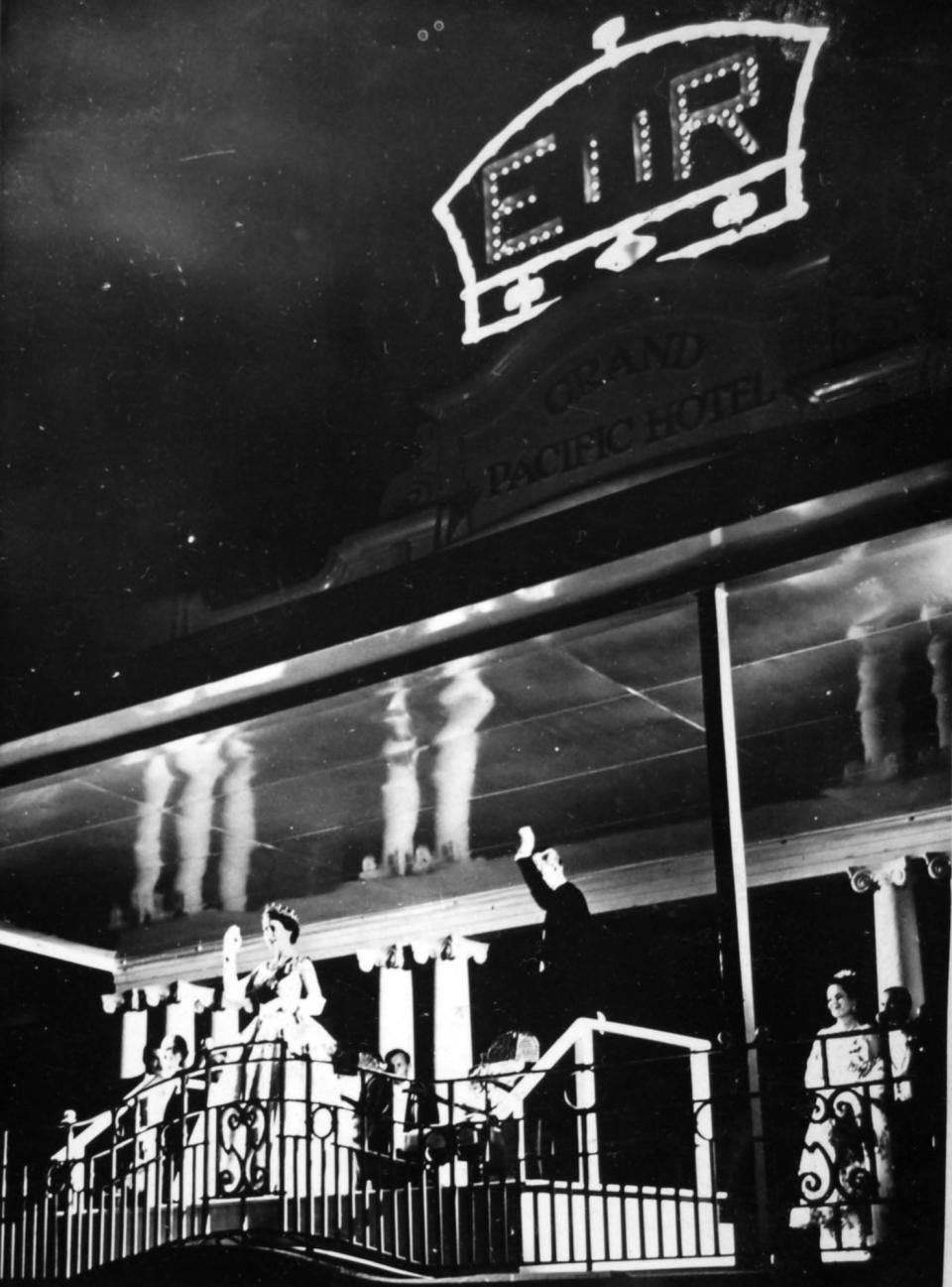 The Queen and Duke of Edinburgh wave from the balcony of the Grand Pacific Hotel in 1953 (PA)