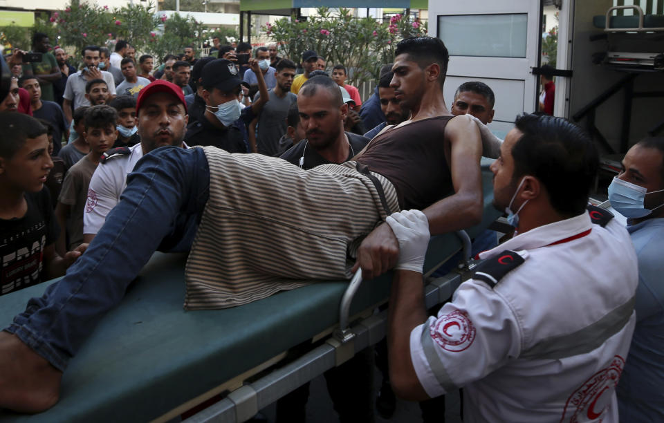 Medics move a wounded youth, who was shot by Israeli troops in his leg during a protest at the Gaza Strip's border with Israel, into the treatment room of Shifa hospital in Gaza City, Saturday, Aug. 21, 2021. (AP Photo/Abdel Kareem Hana)