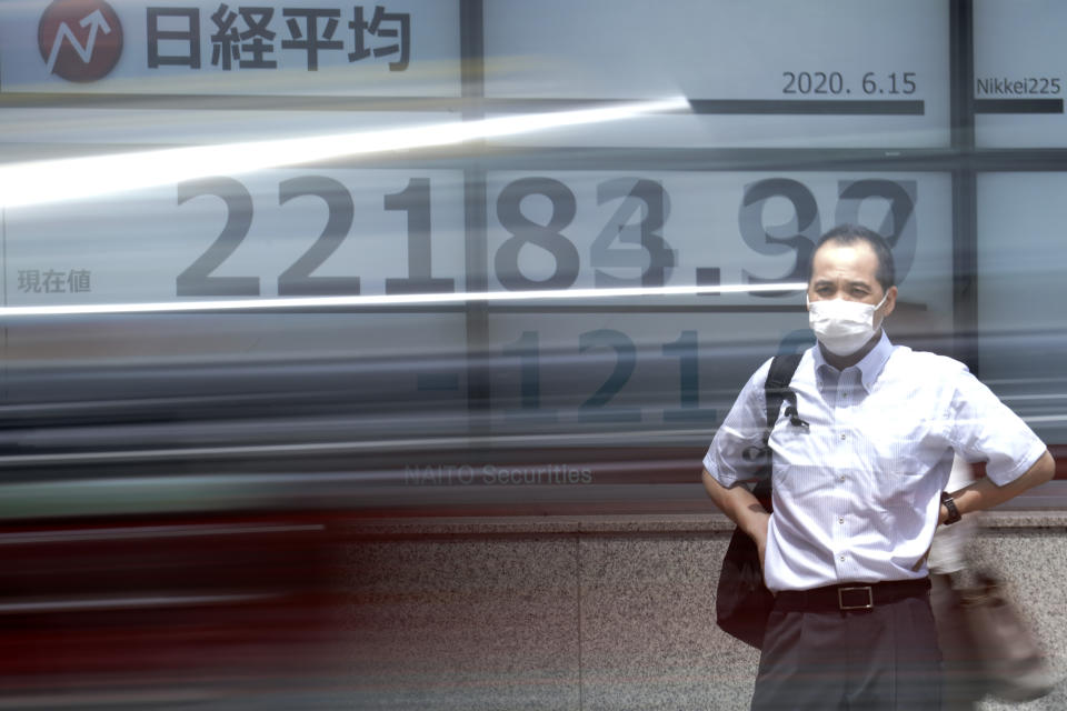 A man stands in front of an electronic stock board showing Japan's Nikkei 225 index as a car passes by at a securities firm in Tokyo Monday, June 15, 2020. Asian shares were mostly lower Monday on concern over a resurgence of coronavirus cases and pessimism after Wall Street posted its worst week in nearly three months. (AP Photo/Eugene Hoshiko)