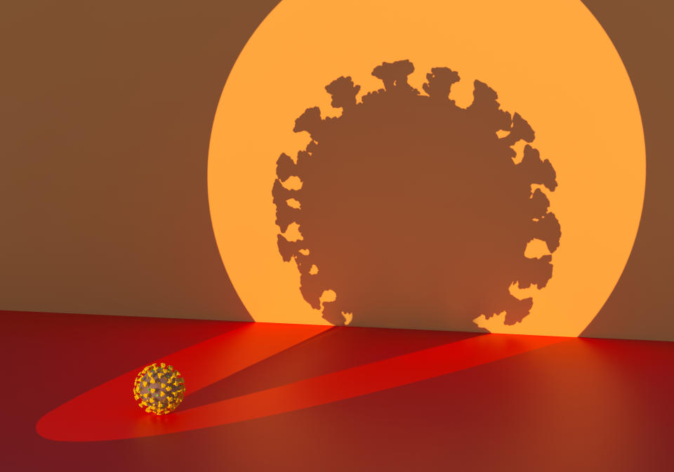 Digital generated image of highlighted by circular spot light coronavirus Covid 19 and projected huhe shadow/silhouette to wall.