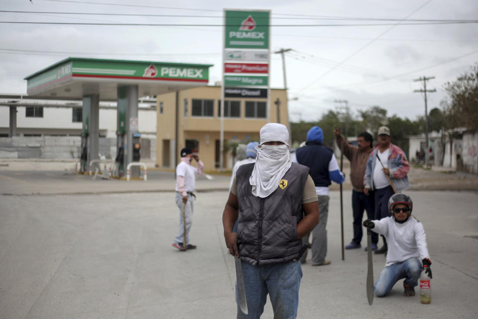 Masked men stand guard in front of a gas station in Veracruz, Mexico, Saturday, Jan. 7, 2017. As looting as largely subsided in Mexico, following a 20 percent hike in gasoline prices, neighborhoods in affected áreas have taken to guarding themselves from potential looters. (AP Photo/Felix Marquez)