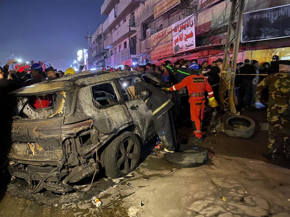 Civil defense members gather at the site of a burned vehicle targeted by a U.S. drone strike in east Baghdad, Iraq, Wednesday, Feb. 7, 2024. (AP Photo/Hadi Mizban)