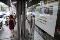 A woman walks beside a sign about hiring domestic helpers for the middle east outside an office in Manila, Philippines on Thursday, Oct. 21, 2021. The Philippines, a leading source of global labor, has fought with alarm the spike in the number of Facebook pages, which have been used for illegal job recruitment and human trafficking in the last two years. Facebook suggested a pilot program to begin in 2021 that targeted Filipinas with pop-up messages and banner ads warning them about the dangers working overseas can pose. (AP Photo/Aaron Favila)