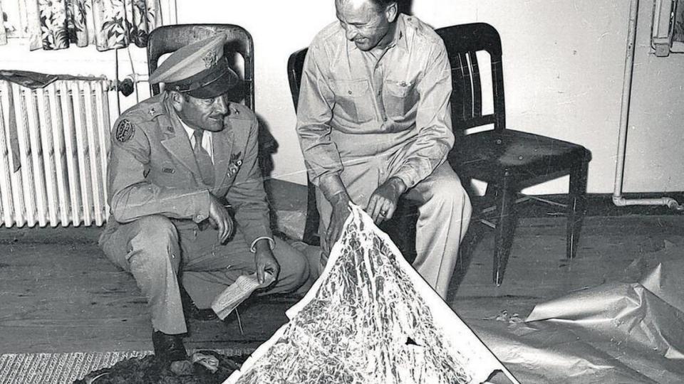 Brig. Gen. Roger Ramey, 8th Air Force commander, left, and Col. Thomas J. Dubose, chief of staff, look over debris flown to Fort Worth Army Air Field (now Naval Air Station Fort Worth) from the mysterious Roswell incident crash near Corona, N.M., in July 1947. The telegram in Ramey’s hand is being studied.