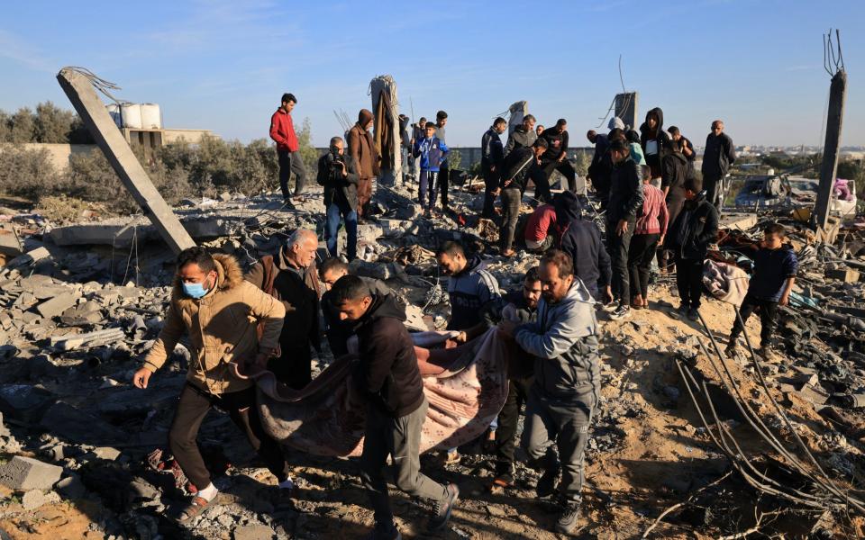 People carry away the body of a victim found under the rubble of a house t