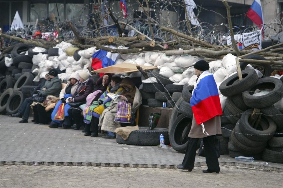 A woman wrapped in a Russian national flag walks in front of a barricade at the regional administration building in Donetsk, Ukraine, Wednesday, April 9, 2014. Ukrainian Interior Minister Arsen Avakov said the standoff in Luhansk and the two neighboring Russian-leaning regions of Donetsk and Kharkiv must be resolved within the next two days either through negotiations or through the use of force, the Interfax news agency reported. (AP Photo/Alexander Ermochenko)