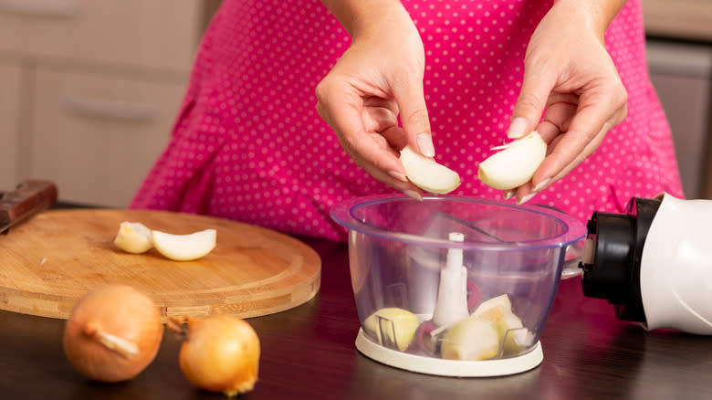 woman putting onions in a food processor