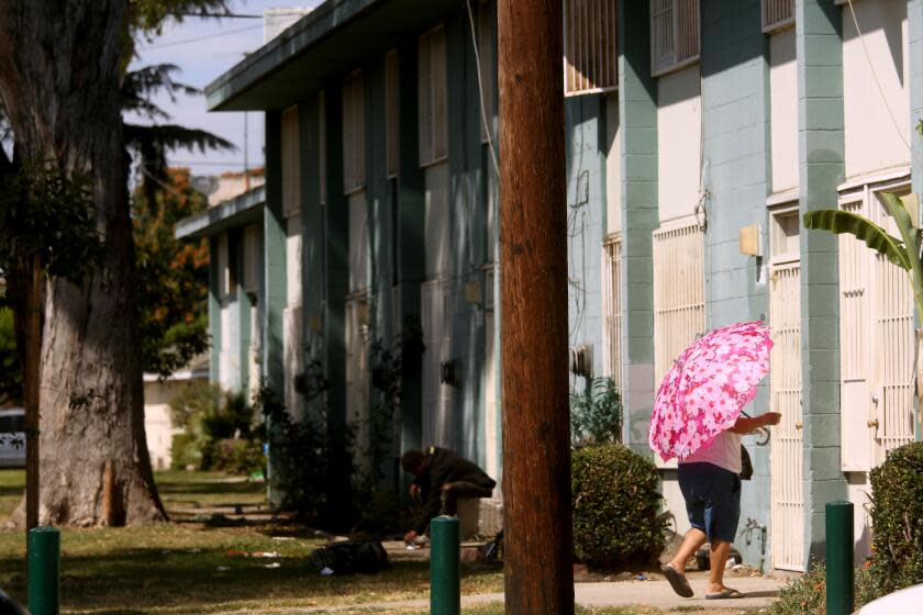 WATTS, CA - AUGUST 1, 2023 - A resident makes her way home at the Imperial Courts housing project in Watts on August 1, 2023. Watts has been the site of violence in recent weeks with multiple people dying and 9 people being shot in Imperial Courts and Jordan Downs housing projects. (Genaro Molina / Los Angeles Times)