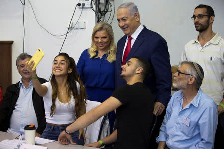 A youth takes a selfie with Israel's Prime Minister Benjamin Netanyahu and his wife Sara after they voted in Israel's parliamentary election in Jerusalem April 9, 2019. Ariel Schalit/Pool via REUTERS