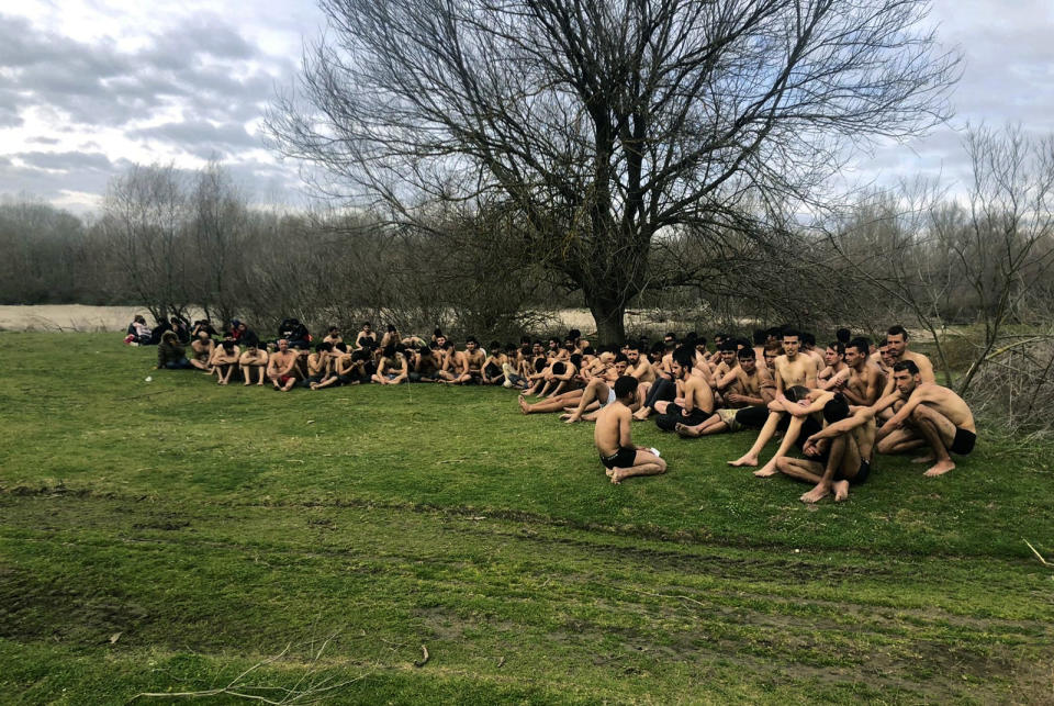 This photo provided by Turkey's IHA news agency taken Thursday, March 5, 2020 purports to show a group of some 100 migrants near the Turkey-Greece border, in Uzunkopru, Edirne, Turkey. The agency says the migrants were sent back to Turkey from Greece by Greek security forces after allegedly being stripped of their clothes on Thursday. The Associated Press has not been allowed into the area. (IHA via AP)