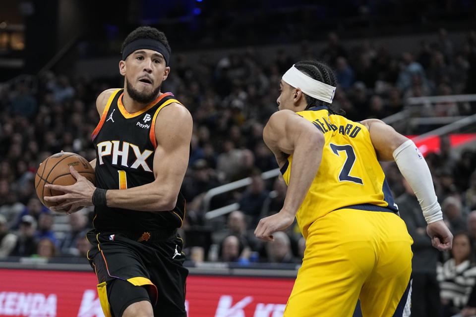 Phoenix Suns' Devin Booker (1) goes to the basket against Indiana Pacers' Andrew Nembhard (2) during the first half of an NBA basketball game Friday, Jan. 26, 2024, in Indianapolis. (AP Photo/Darron Cummings)