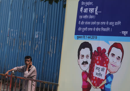 A man speaks on a phone next to a hoarding with cartoons of India's main opposition Congress Party President Rahul Gandhi and Sanjay Nirupam, President of the Mumbai Regional Congress Committee, alongside a road in Mumbai, February 22, 2019. REUTERS/Francis Mascarenhas