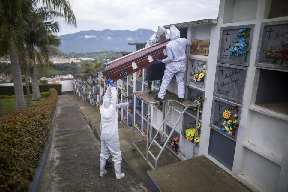 Cemetery and funeral workers place the coffin of a man who died of COVID-19 into a niche at the Nuestra Señora de Belen cemetery in Fusagasuga, Colombia, Wednesday, June 9, 2021. (AP Photo/Ivan Valencia)