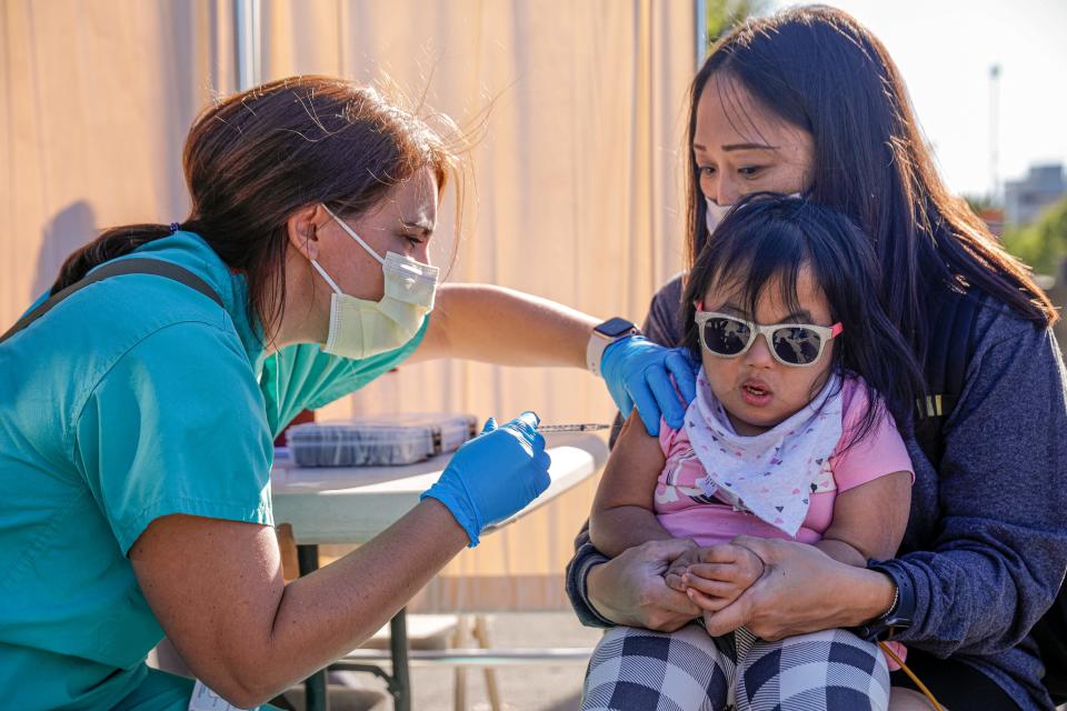 Dr. Allison Lopez, left, gives Julia Choe, 5, her first dose of a COVID-19 vaccine while she sits on her mother Trisha's lap at a mobile clinic in November. Soon kids younger than 5 will be able to get a COVID-19 vaccine.