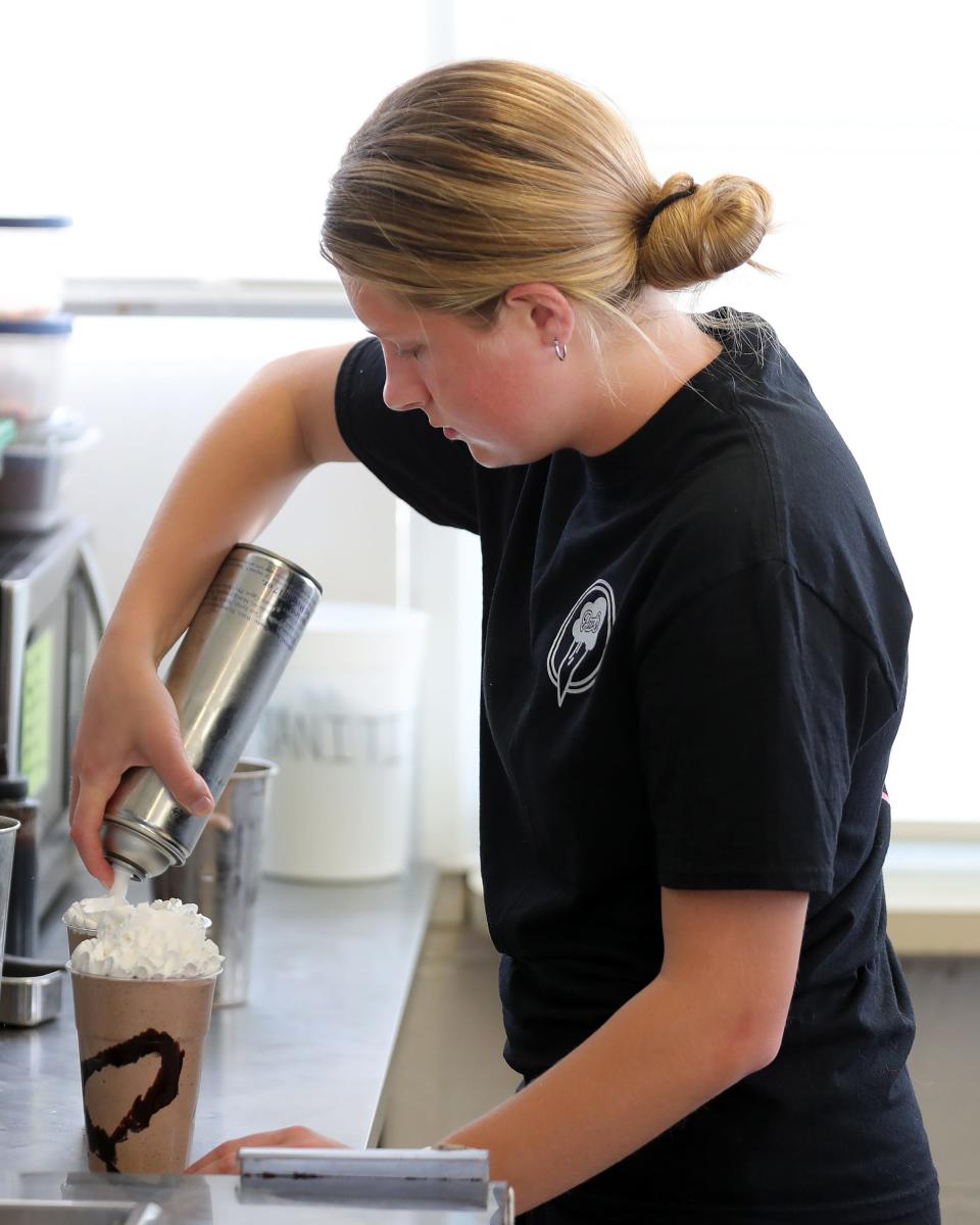 Jenna Ruether adds whipped cream to a chocolate peanut butter milkshake at Pav's Creamery in Coventry Township.