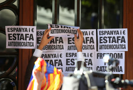 A crowd of protesters paste posters reading "Spain and Euro, Anti-democratic Fraud" to the Catalan region's economy ministry building after junior economy minister Josep Maria Jove was arrested by Spanish police during a raid on several government offices, in Barcelona, Spain, September 20, 2017. REUTERS/Albert Gea