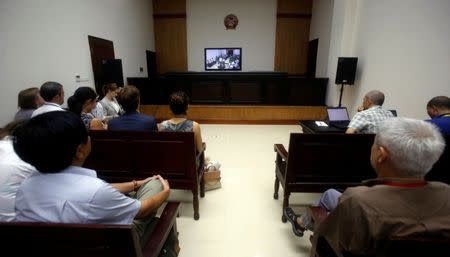 Members of the media and diplomats watch a live screen from the courtroom showing Vietnamese prominent blogger Anh Ba Sam whose real name is Nguyen Huu Vinh (L), and his assistant Nguyen Thi Minh Thuy during their appeal trial in Hanoi, Vietnam September 22, 2016. REUTERS/Kham