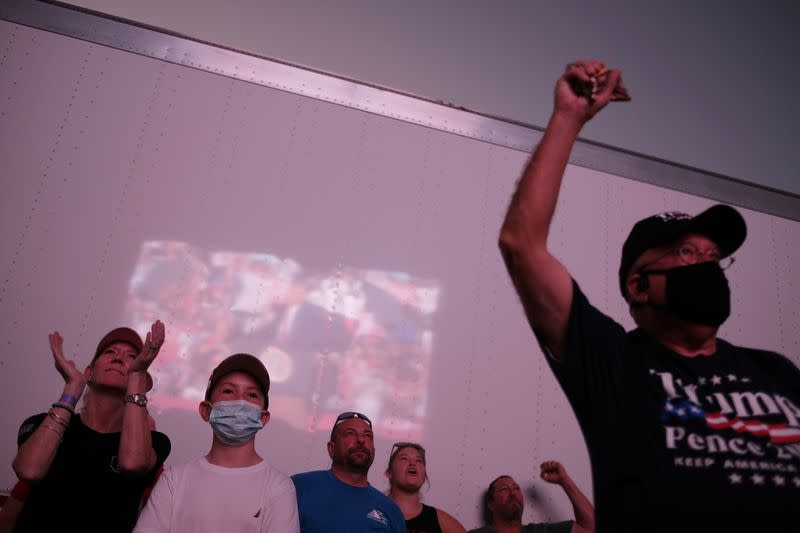 Supporters of U.S. President Donald Trump watch the president's speech projected on a giant screen placed on the outside as is reflected on a cargo container during an election campaign rally at Orlando Sanford International Airport